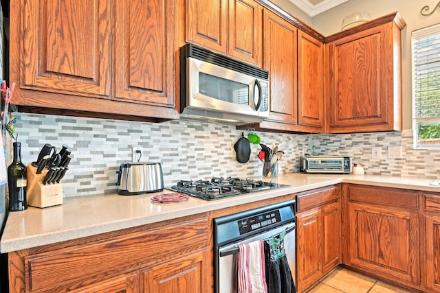 202 Beacon Hill Ln, Forney, TX 75126 - kitchen featuring stainless steel appliances, brown cabinets, ornamental molding, light countertops, and decorative backsplash
