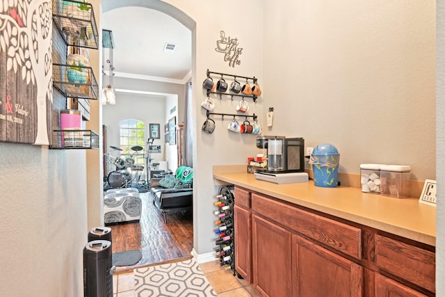 202 Beacon Hill Ln, Forney, TX 75126 - bar with arched walkways, crown molding, and light tile patterned flooring