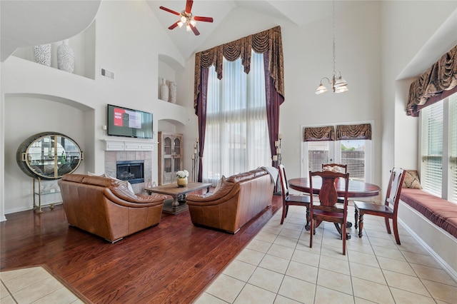 5808 Arabian Dr, Grand Prairie, TX 75052 - living area with light tile patterned flooring, a tiled fireplace, baseboards, ceiling fan with notable chandelier, and high vaulted ceiling