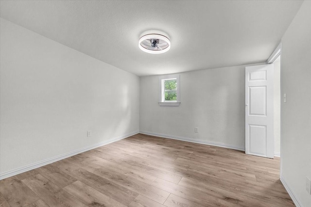 empty room with light wood finished floors, baseboards, and ceiling fan