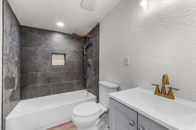 bathroom with a textured ceiling, vanity, a textured wall, toilet, and visible vents