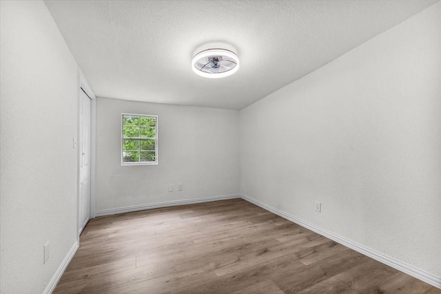 unfurnished room featuring baseboards, wood finished floors, and a textured ceiling