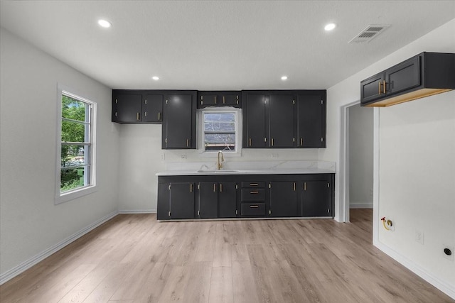 kitchen with dark cabinets, a sink, visible vents, and light countertops