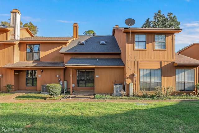 back of property featuring a lawn, a shingled roof, and central air condition unit