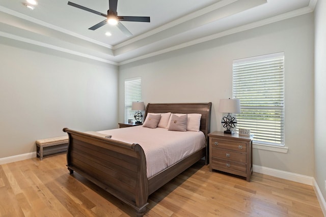 bedroom featuring light wood-type flooring, baseboards, ornamental molding, and a raised ceiling