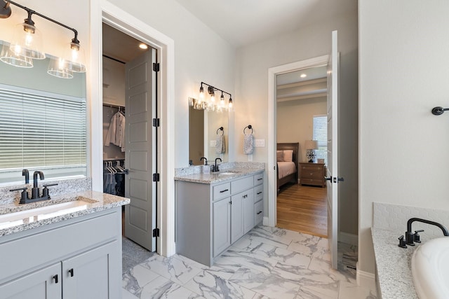 bathroom with two vanities, plenty of natural light, marble finish floor, and a sink