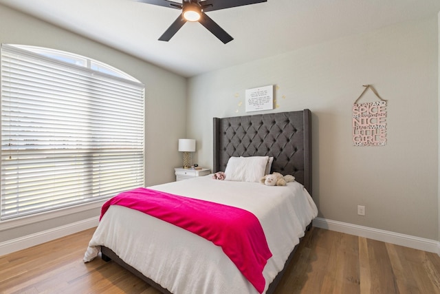 bedroom featuring light wood-type flooring, a ceiling fan, and baseboards