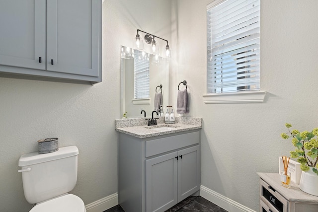 bathroom with vanity, toilet, and baseboards