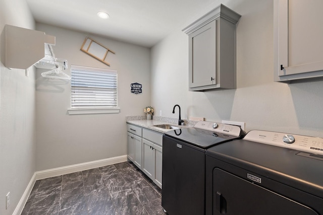 laundry area featuring cabinet space, baseboards, washer and dryer, and a sink