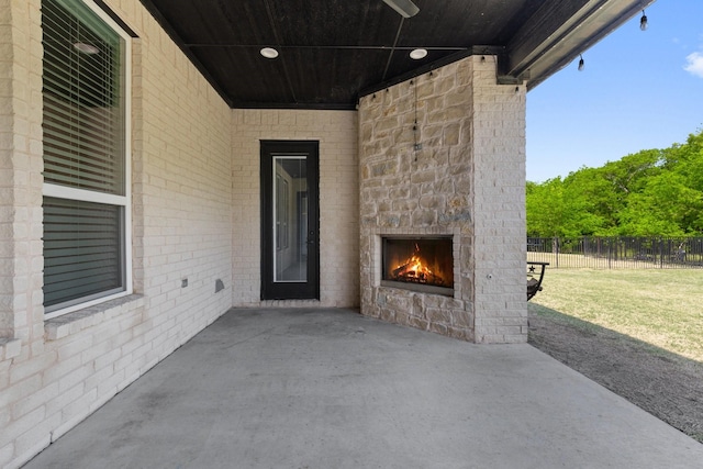 view of patio with fence and an outdoor stone fireplace
