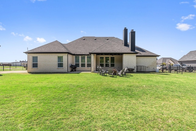 back of house with a fenced backyard, a yard, and a shingled roof