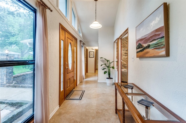 foyer entrance with baseboards and a textured wall
