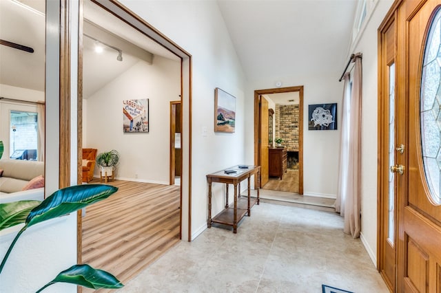 hall featuring lofted ceiling and baseboards