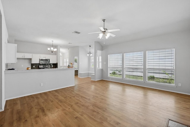 909 Whisper Ln, Mckinney, TX 75072 - unfurnished living room with a chandelier, plenty of natural light, light wood-type flooring, and a ceiling fan