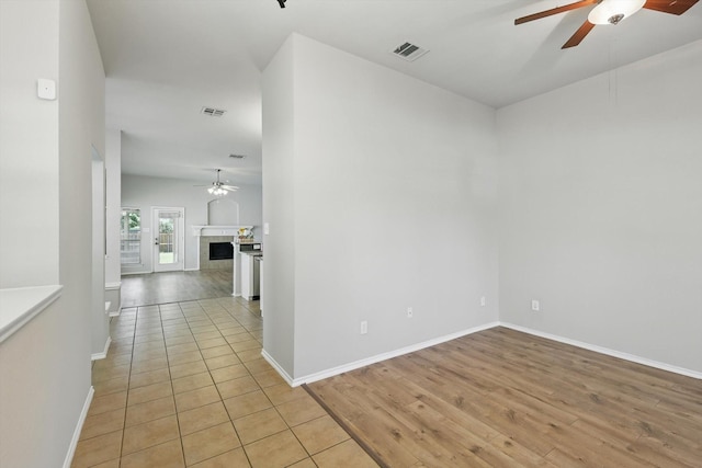 909 Whisper Ln, Mckinney, TX 75072 - unfurnished room featuring ceiling fan, light wood-style floors, and a tiled fireplace