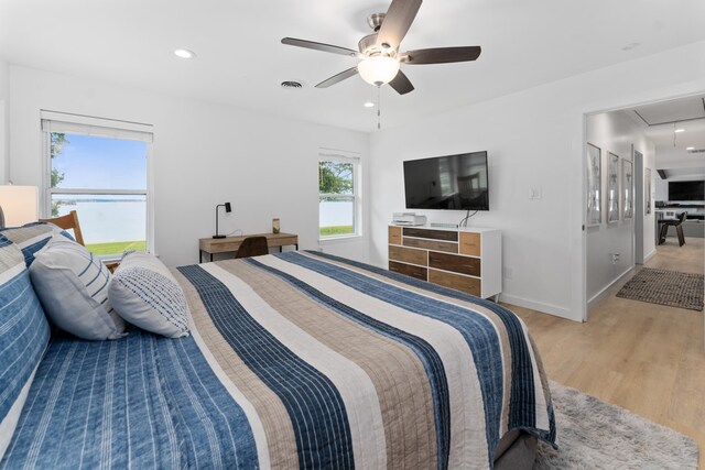 bedroom featuring attic access, ceiling fan, light wood-type flooring, visible vents, and baseboards