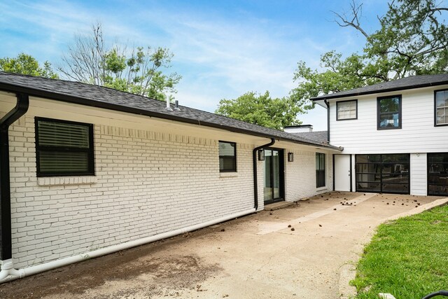 view of front of house with brick siding, concrete driveway, and a patio area