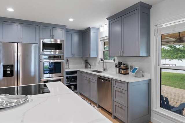 kitchen featuring appliances with stainless steel finishes, gray cabinetry, recessed lighting, and a sink