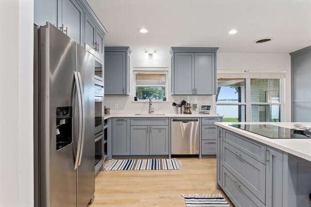 kitchen featuring gray cabinetry, a sink, stainless steel appliances, and visible vents