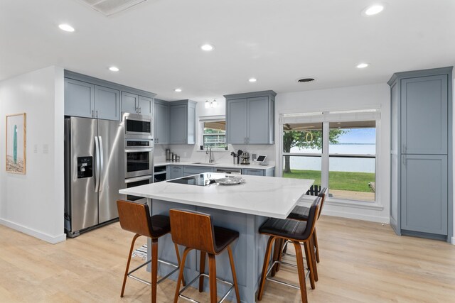 kitchen with a kitchen breakfast bar, stainless steel appliances, light wood finished floors, and baseboards