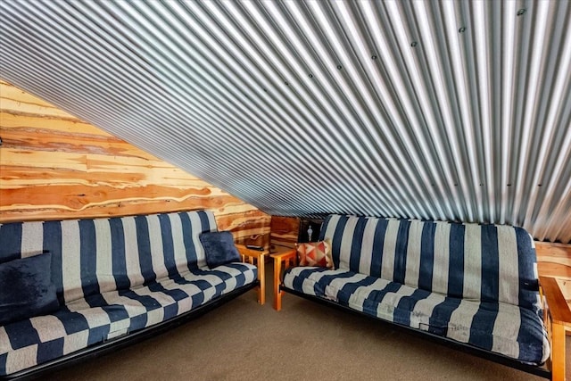 carpeted living area with wooden walls and vaulted ceiling