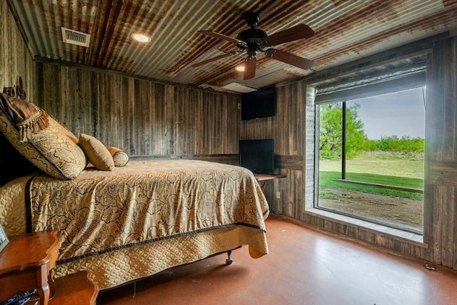 bedroom featuring a ceiling fan, concrete floors, wood walls, and visible vents