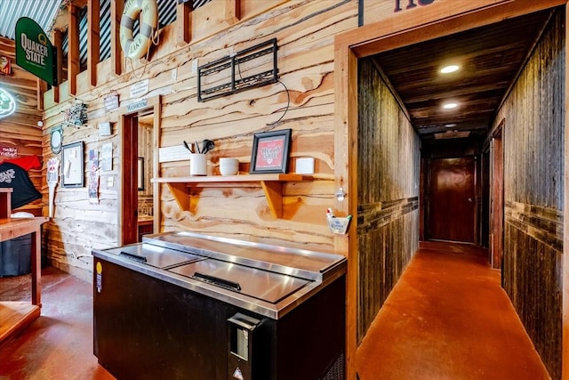hall with wood walls and finished concrete floors