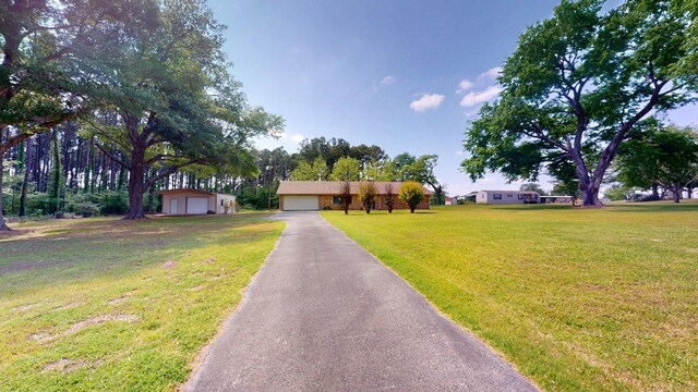 view of front facade featuring an outdoor structure, a detached garage, and a front yard