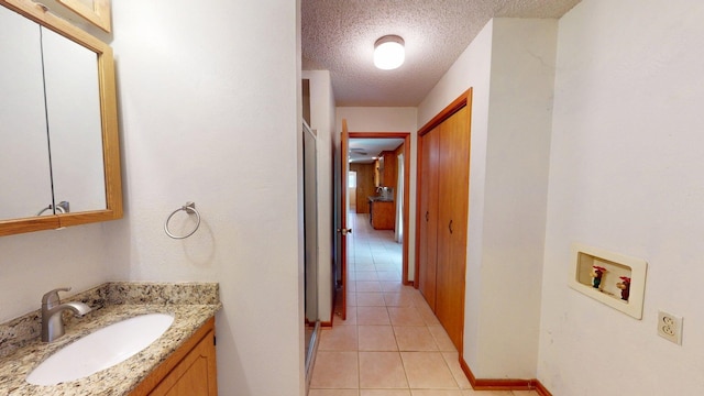 bathroom with baseboards, a textured ceiling, tile patterned floors, and vanity