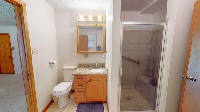 bathroom featuring tile patterned floors, a textured ceiling, toilet, a shower stall, and vanity