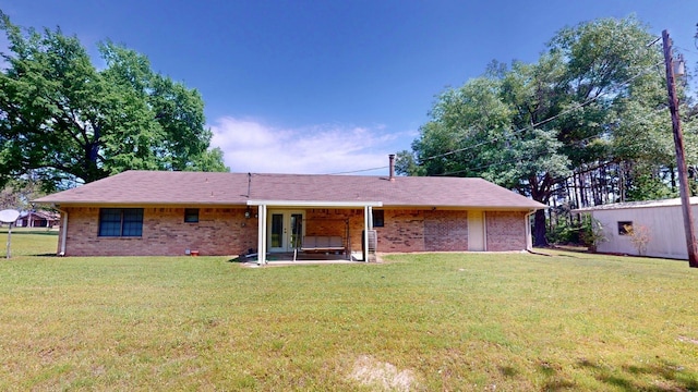 rear view of house featuring brick siding, a yard, and french doors