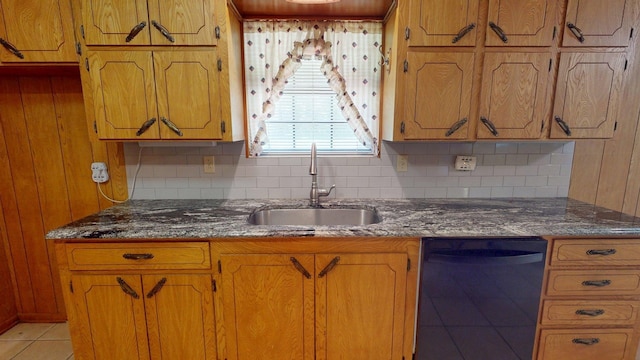 kitchen featuring brown cabinetry, a sink, black dishwasher, and tasteful backsplash
