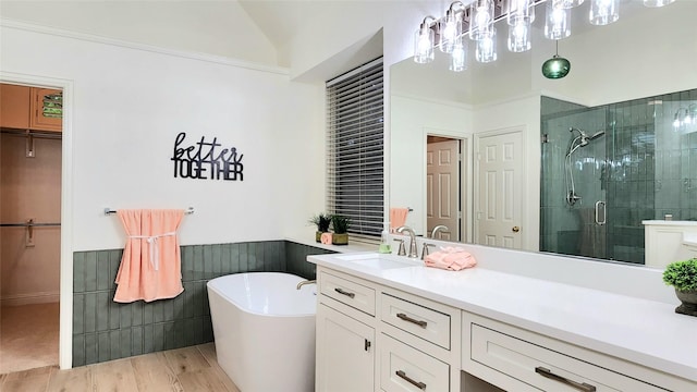 4406 Bay Valley Dr, Garland, TX 75043 - bathroom featuring wood finished floors, a stall shower, vanity, a freestanding tub, and lofted ceiling