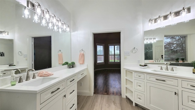 4406 Bay Valley Dr, Garland, TX 75043 - bathroom featuring two vanities, wood finished floors, a towering ceiling, and a sink