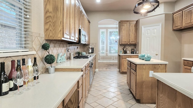 4406 Bay Valley Dr, Garland, TX 75043 - kitchen featuring stainless steel appliances, arched walkways, tasteful backsplash, light countertops, and a kitchen island