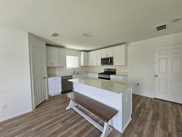 1020 Valerian Dr, Haslet, TX 76052 - kitchen featuring stainless steel appliances, dark wood-style flooring, light countertops, white cabinets, and a textured ceiling