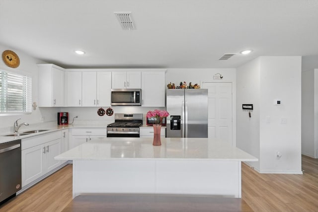 1020 Valerian Dr, Haslet, TX 76052 - kitchen with appliances with stainless steel finishes, a sink, light wood-type flooring, white cabinetry, and recessed lighting