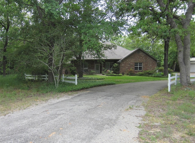 view of front facade with brick siding, aphalt driveway, and a front yard