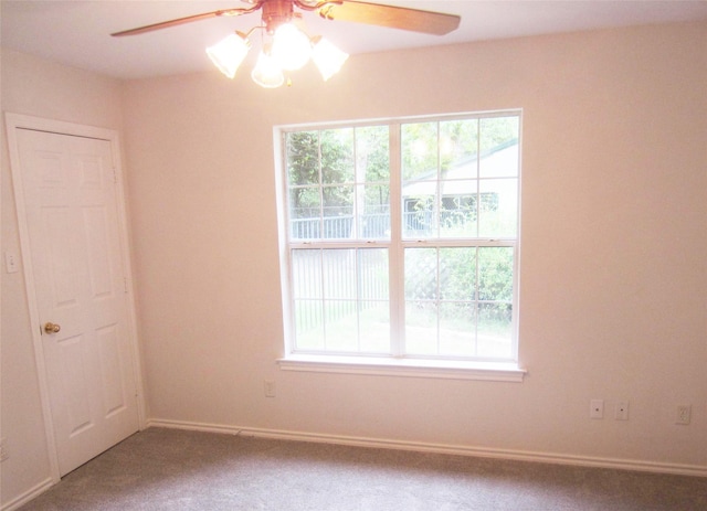carpeted spare room featuring ceiling fan and baseboards