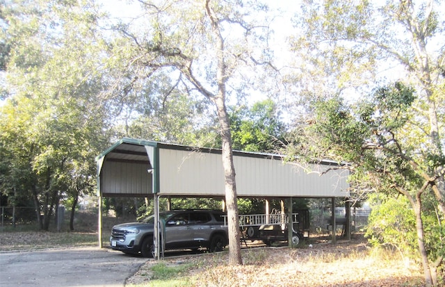 view of parking / parking lot with a carport, driveway, and fence