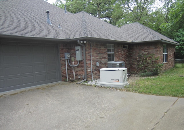 view of side of property with a shingled roof, driveway, brick siding, and a garage