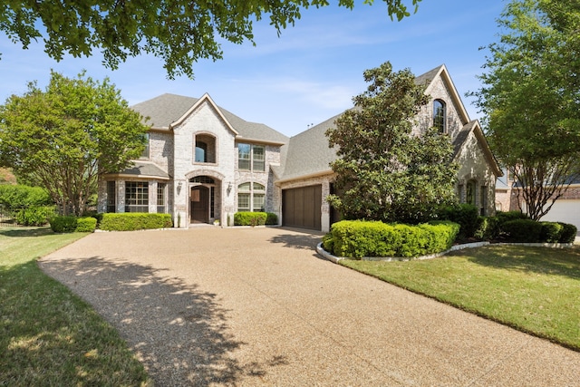 1191 Broken Bend Dr, Prosper, TX 75078 - french country style house featuring driveway, a garage, stone siding, and a front lawn