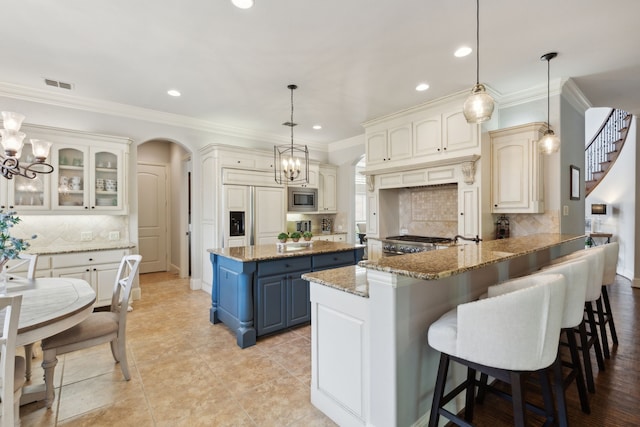 1191 Broken Bend Dr, Prosper, TX 75078 - kitchen featuring blue cabinetry, built in appliances, a chandelier, backsplash, and arched walkways