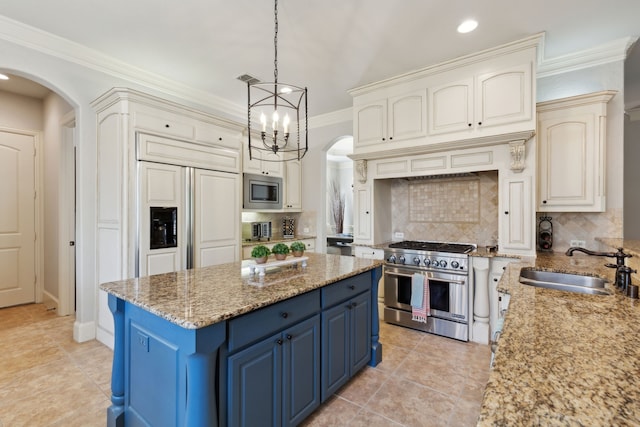 1191 Broken Bend Dr, Prosper, TX 75078 - kitchen featuring blue cabinets, built in appliances, arched walkways, backsplash, and ornamental molding