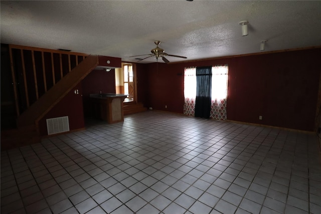 unfurnished living room featuring stairs, a textured ceiling, light tile patterned floors, ceiling fan, and visible vents