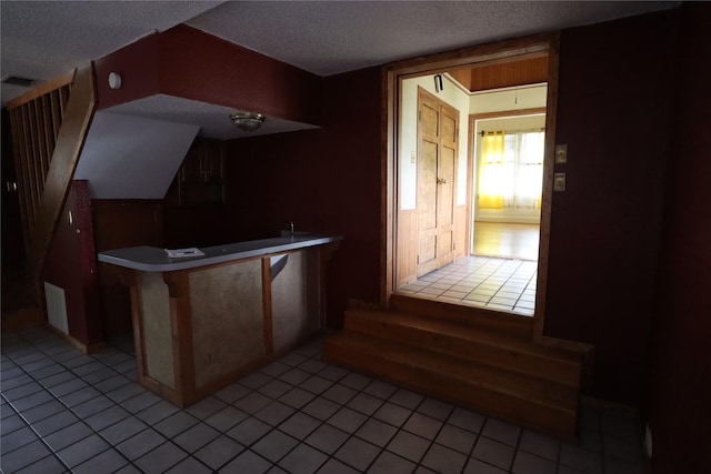 kitchen with a peninsula, visible vents, a textured ceiling, and light tile patterned flooring