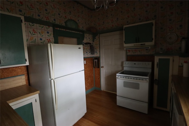 kitchen with wallpapered walls, wood finished floors, an inviting chandelier, and white appliances