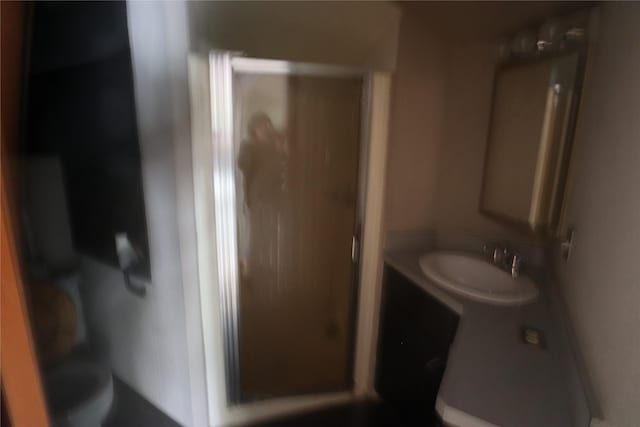 bathroom featuring toilet, vanity, and a stall shower