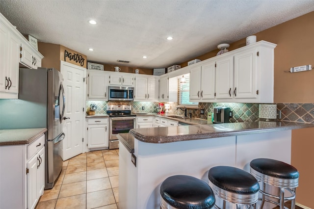 3451 Sudith Ln, Midlothian, TX 76065 - kitchen featuring appliances with stainless steel finishes, a sink, a peninsula, white cabinets, and decorative backsplash