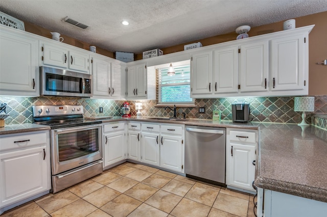 3451 Sudith Ln, Midlothian, TX 76065 - kitchen with stainless steel appliances, a sink, white cabinets, decorative backsplash, and a textured ceiling